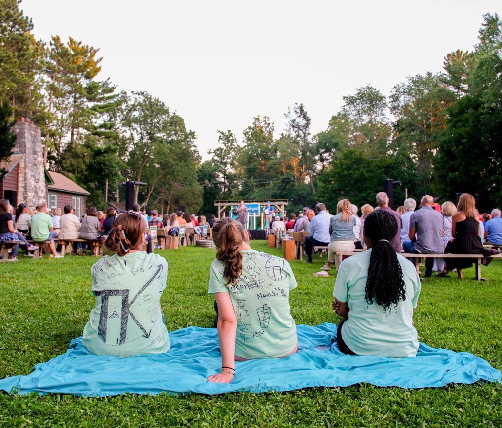 girls on blanket listening at outdoor event